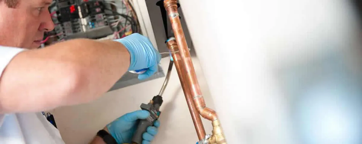 Water heater repair technician testing copper pipe connections and controls in Berkeley, CA